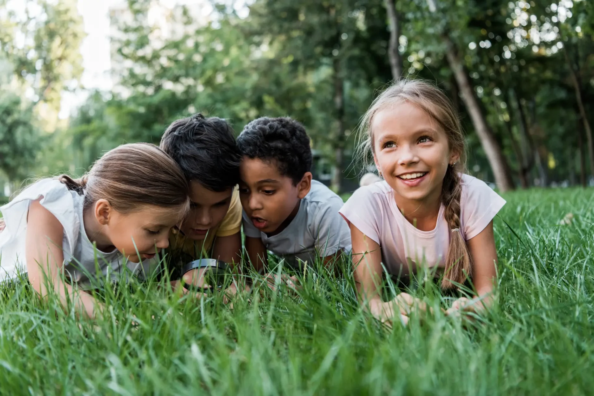 Kids laying in grass looking at bugs